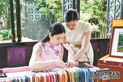 在余荫山房的标志性景点玲珑水榭，广绣传承人梁秀玲和她的女儿一起展示广绣针法。